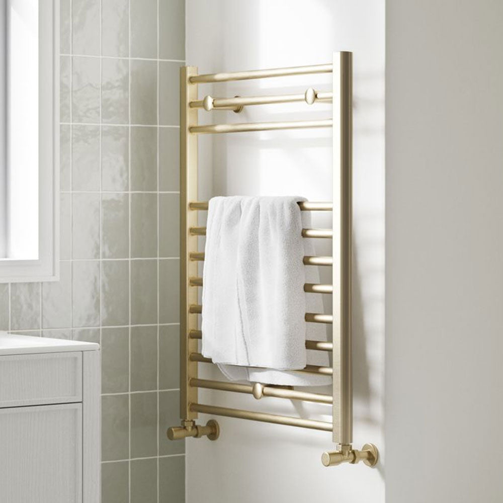 Brushed brass heated towel radiator with a towel in a bathroom