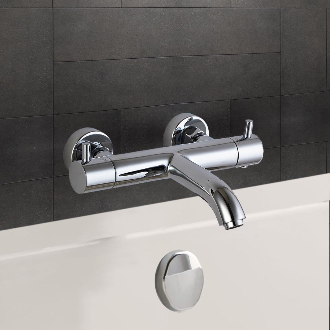 Chrome wall-mounted bath mixer above a white bath against dark wall tiles