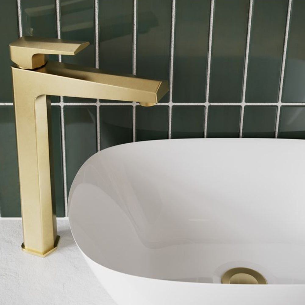 Brushed brass tap beside a white basin against dark green tiles